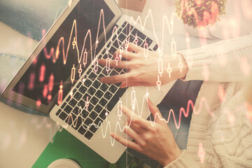 Double exposure of woman hands working on computer and forex chart hologram drawing. Top View....