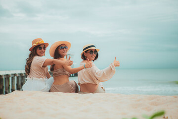 three asian woman sitting on vacation sea beach with happinessw emotion