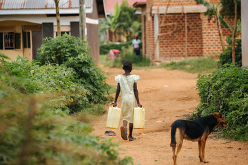 Child carrying water cans in Uganda, Africa