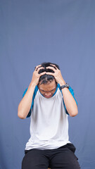 asian man stress gesture and expression holding head and hair with isolated blue background