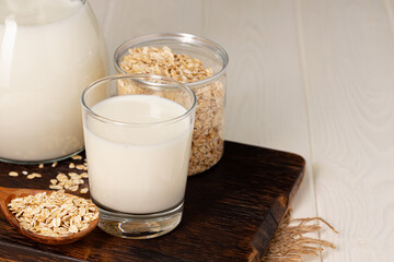 Glass of milk and oat flakes on wooden table