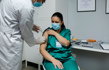 Female surgeon receiving coronavirus vaccine at doctor's office