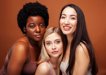 Obraz premium young pretty asian, caucasian, afro woman posing cheerful together on brown background, lifestyle diverse nationality people concept