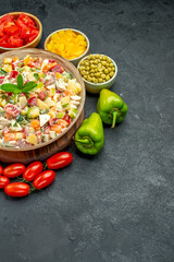 side view of bowl of vegetable salad with vegetables on side with free space for your text on dark grey background