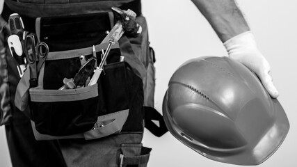 Construction worker with tools and safety helmet. Man builder holds hard hat. Building improvement...