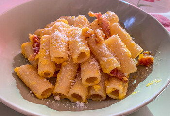 Piatto di rigatoni alla carbonara con guanciale croccante, uova e formaggio grattugiato