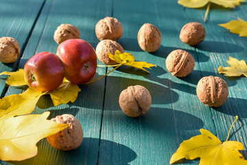 Apple, fallen leaves and ripe walnuts on the table