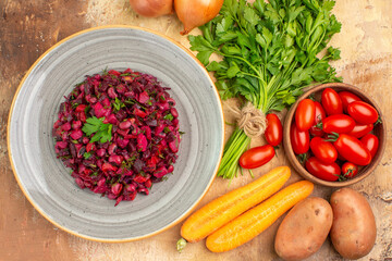 top view beetroot salad on a ceramic plate and ingredients for its preparation on a wooden background