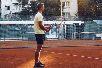 Young handsome man playing tennis on the tennis court