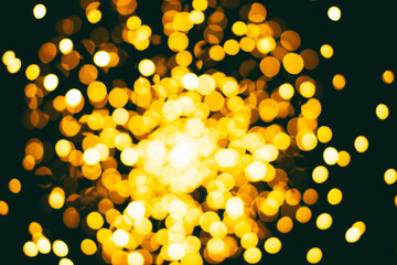 Yellow shining gold glare bokeh on dark background, festive background