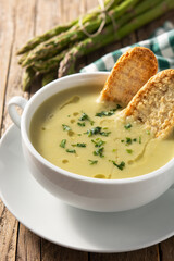 Fresh green asparagus soup in bowl on wooden table