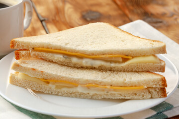 Toast sandwich and cup of coffee on napkin on wooden table