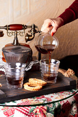Woman Barista's hand pouring hot alternatively brewed coffee from glass jug to glasses