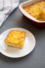 Homemade Cheesy Amish Breakfast Casserole on gray background, low angle view.