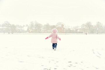 little girl walks in heavy snow. back view