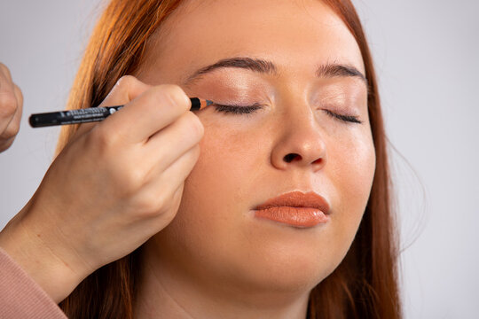 Closeup photo of make up for a red-haired girl, closed eyes and a eyeliner cosmetic pencil. Beauty concept.