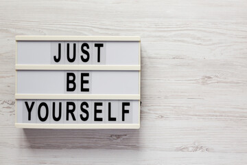 'Just be yourself' on a lightbox on a white wooden surface, top view. Flat lay, overhead, from above. Space for text.