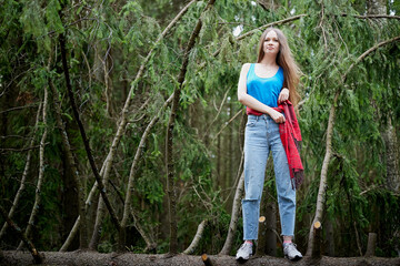 Beautiful young brunette woman with long hair in a forest pines and firs on a summer day