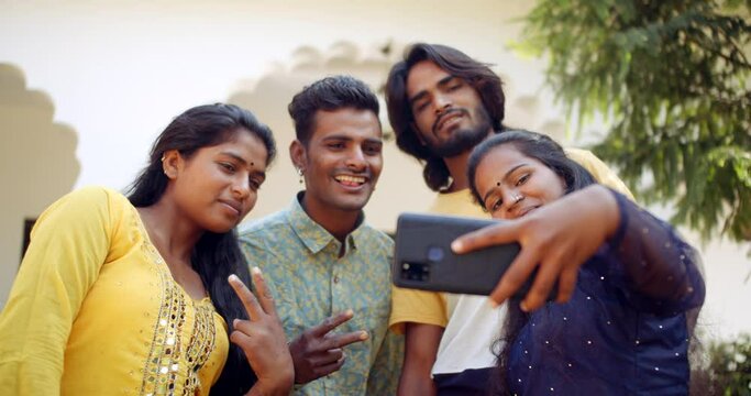 Slow-motion shot of Young adult females and males outside their university campus building taking a selfie photo video on their mobile phone camera smiling happy joyous 