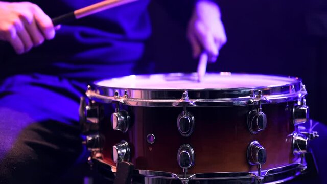 Man playing on snare drum with drumsticks. Closeup.