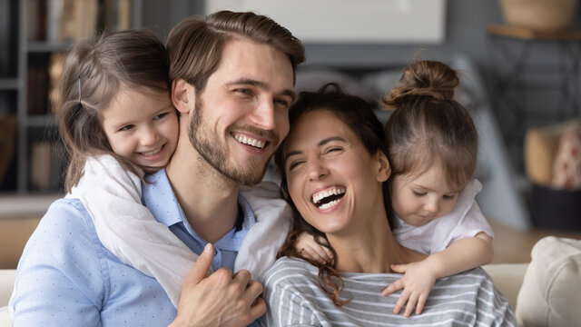 Close up wide banner panoramic view of happy young Caucasian family with two small daughters have fun at home. Smiling mom and dad feel playful enjoy weekend relaxing with little girls children.