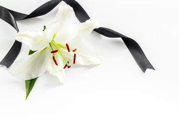 Funeral symbols - white lily flowers with black ribbon