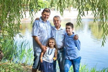 Banner with a happy family on a walk in the summer. Grandfather, father, son and daughter communicate and have fun in nature. Family values ​​concept. Three generations. Love and trust.