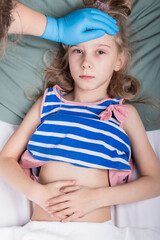studio lighting. child, schoolboy with white hair lies in bed. The doctor examines the girl.