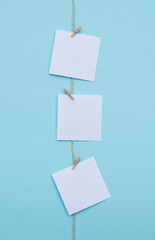 three blank note papers attached to a rope on vertical blue background