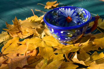 Decorative cup on fallen leaves on the table