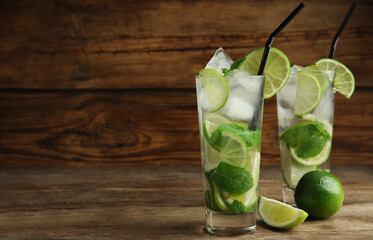 Delicious mojito and ingredients on wooden table. Space for text