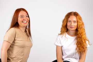 Red-haired cute girlfriends on a white background smiling and posing for the camera. Free space for advertisment