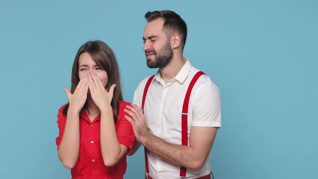 Displeased frustrated quarreling young couple friends bearded man woman in white red clothes posing isolated on blue background studio. People lifestyle concept. Spreading hand crying swearing hugging
