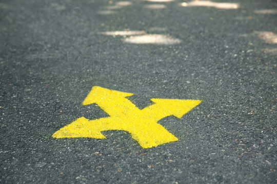 Bright yellow arrows painted on asphalt road