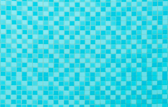Blue pool tiles mosaic ceramics pattern under clear blue water, swimming pool tiles background
