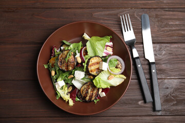 Delicious salad with roasted eggplant, feta cheese and arugula served on wooden table, flat lay