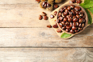 Fresh sweet edible chestnuts on wooden table, flat lay. Space for text