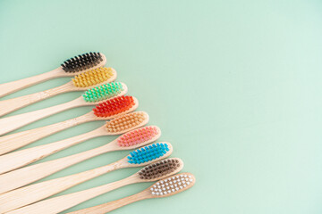 A set of Eco-friendly antibacterial toothbrushes made of bamboo wood on a light green background. Environmental care trends