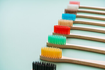 A set of Eco-friendly antibacterial toothbrushes made of bamboo wood on a light green background. Environmental care trends