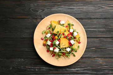 Delicious persimmon salad with pomegranate and feta cheese on wooden table, top view