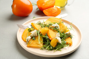 Delicious persimmon salad with blue cheese and orange on light grey table