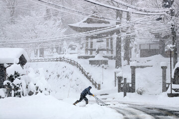  大雪の中で雪かきをする人（豪雪地帯のイメージ）