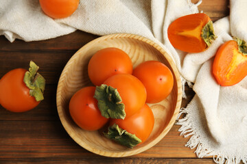 Tasty ripe persimmons on wooden table, flat lay