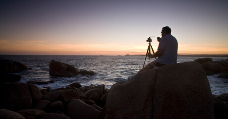 Photographer on coastal rocks sunset