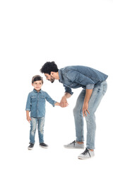 Hispanic father holding hand of smiling son on white background, two generations of men
