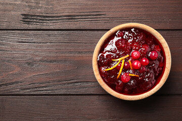 Cranberry sauce with orange peel on wooden table, top view. Space for text