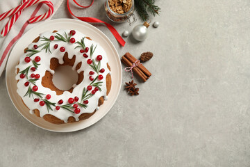 Flat lay composition with traditional Christmas cake and decorations on light grey table, space for text