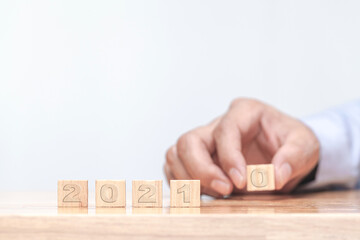 Hand is changing a wooden cube symbolically changes from 2020 to 2021