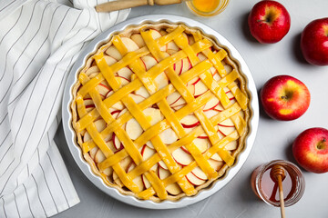 Raw traditional English apple pie in baking dish on light grey table, flat lay