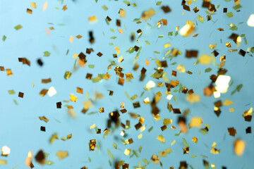 Shiny golden confetti falling down on light blue background - obrazy, fototapety, plakaty